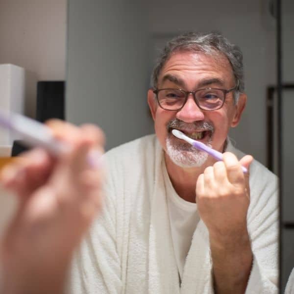 a man brushing his teeth in the mirror